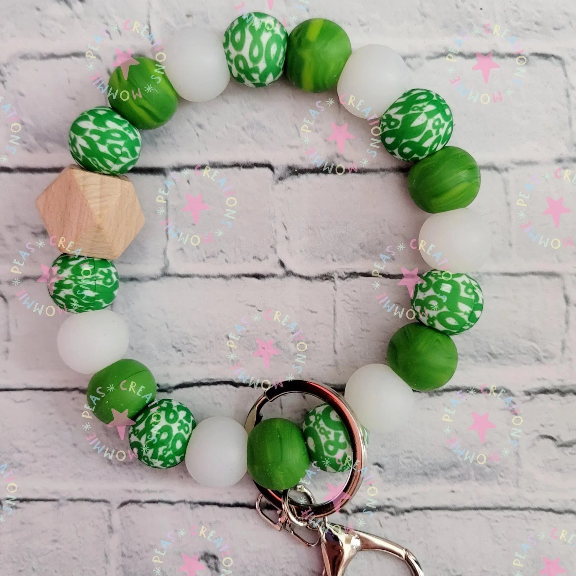 Mommie Peas Creations green and white silicone bead wristlet with wooden accent and green ribbon charm, featuring a swivel snap hook for keys.