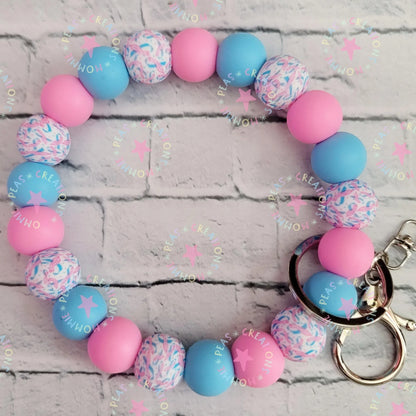 Mommie Peas Creations pink and blue silicone beaded wristlet keychain with infant loss awareness ribbon pattern and star details.