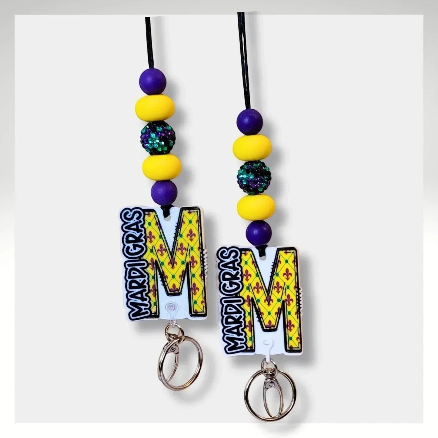 Mommie Peas Creations Mardi Gras initial lanyard with purple, yellow, and green beads and a large letter M charm.