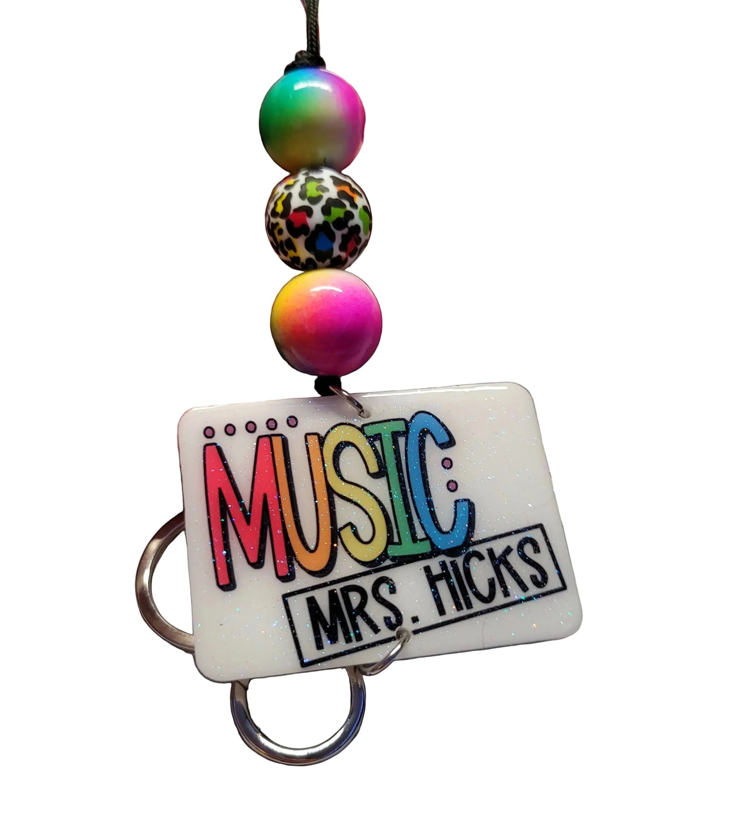 Mommie Peas Creations white rectangular badge holder with "MUSIC MRS. HICKS" text, rainbow and leopard print beads, and silver keyrings.