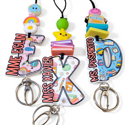 Colorful handmade teacher lanyards with personalized names, rainbow, star, and school bus charms from Mommie Peas Creations