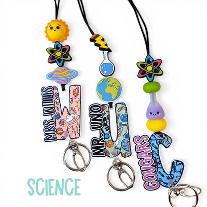Mommie Peas Creations personalized teacher lanyard with science-themed acrylic charms, silicone beads, and custom letter charms.