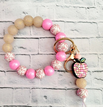 Mommie Peas Creations pink and gold beaded wristlet keychain with a pink apple charm and gold hardware.