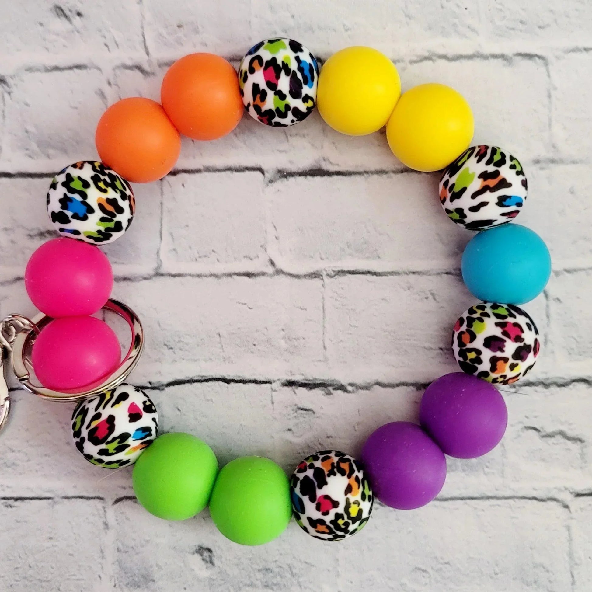 Mommie Peas Creations rainbow leopard print silicone beaded wristlet keychain with bright pink, orange, yellow, teal, purple, and green beads.