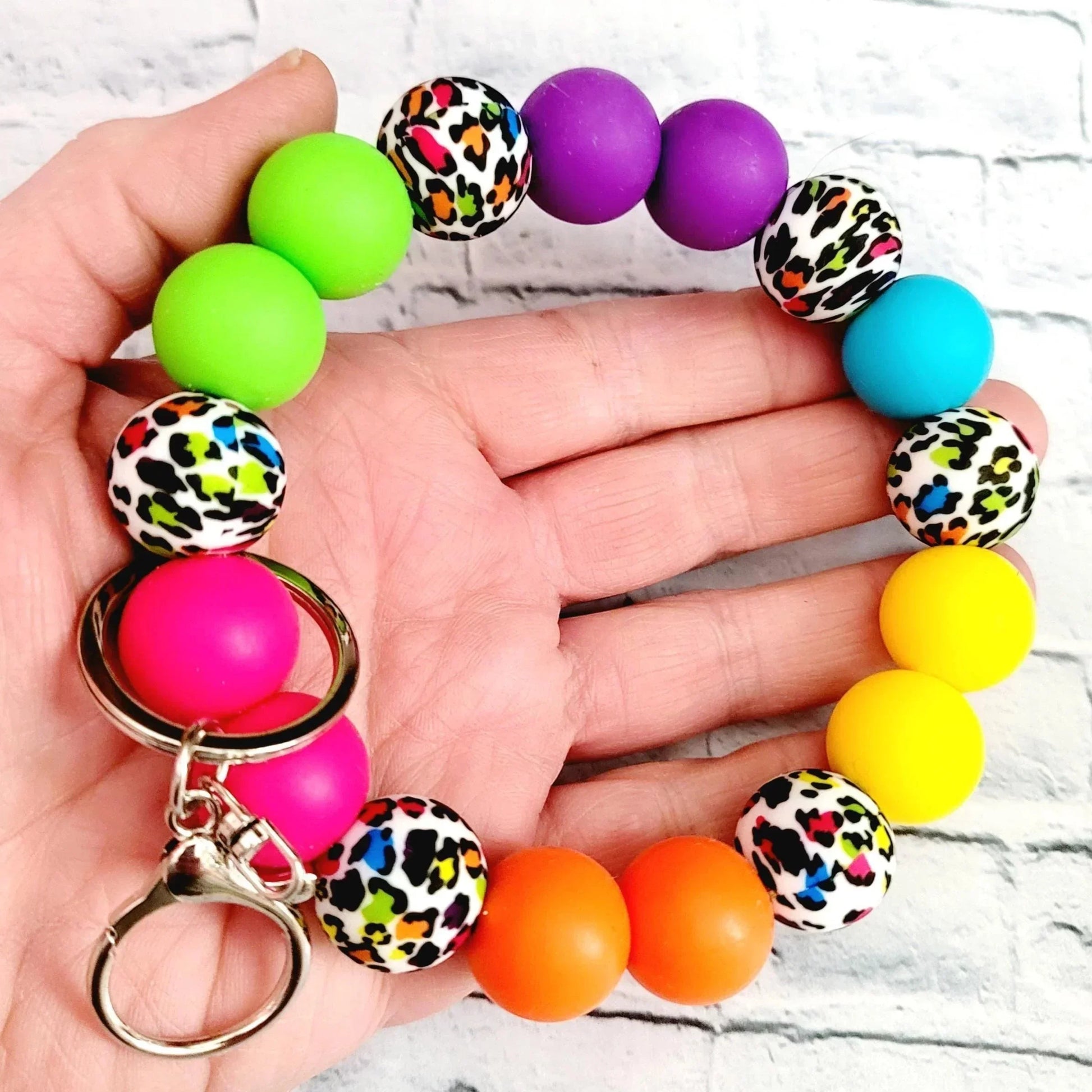 Mommie Peas Creations rainbow leopard print silicone beaded wristlet keychain with bright pink, lime green, purple, turquoise, yellow, and orange beads.
