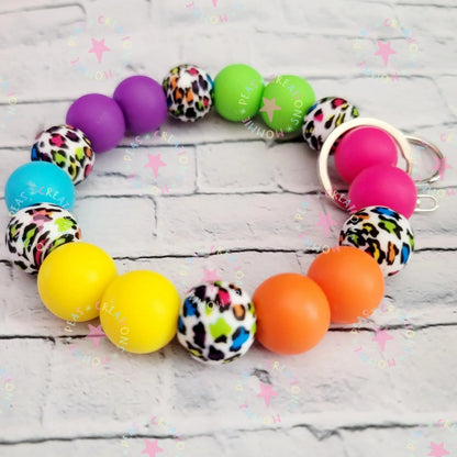 Mommie Peas Creations rainbow leopard print silicone beaded wristlet keychain with bright solid color beads and silver hardware.