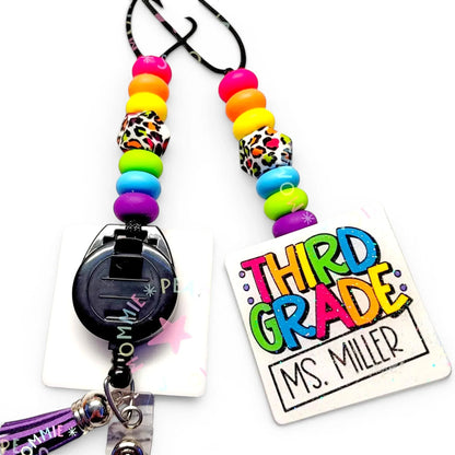 Mommie Peas Creations rainbow leopard print teacher lanyard with silicone beads and a 'Third Grade Ms. Miller' badge holder.