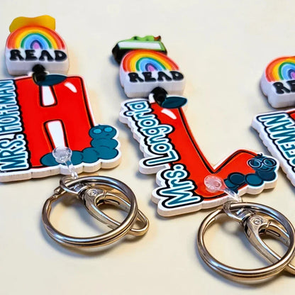 Mommie Peas Creations red apple lanyard with "READ" rainbow charm and personalized name for teachers.