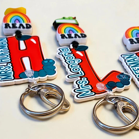 Mommie Peas Creations red apple lanyard with "READ" rainbow charm and personalized name for teachers.