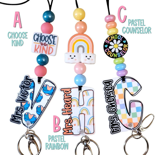 Mommie Peas Creations school counselor lanyard with pastel beads, rainbow, and custom name acrylic charms. Features a breakaway clasp and keychain.