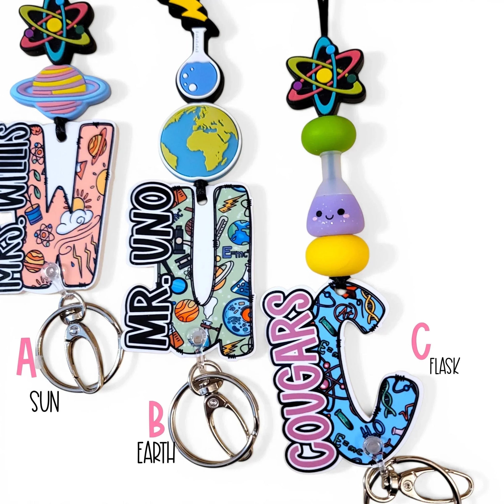 Mommie Peas Creations science lanyard with planet, earth, and flask charms, colorful silicone beads, and personalized acrylic letters.
