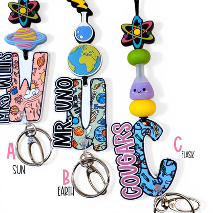 Mommie Peas Creations science lanyard with planet, earth, and flask charms, colorful silicone beads, and personalized acrylic letters.