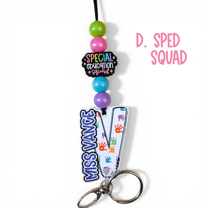 Mommie Peas Creations special education lanyard with "SPED SQUAD" charm, colorful beads, and personalized acrylic ID holder with handprints.