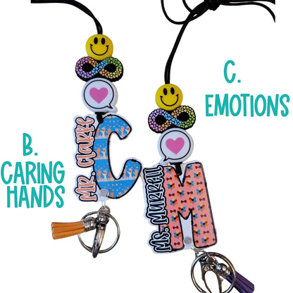 Mommie Peas Creations custom acrylic lanyards for special education teachers. Features smiley face, infinity symbol, heart, and personalized letters with unique designs like 'Caring Hands' and 'Emotions'.