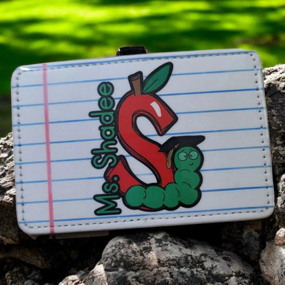 Mommie Peas Creations horizontal PU leather teacher badge holder with a red apple shaped letter S, a green caterpillar wearing a graduation cap, and the text "Ms. Shadee".