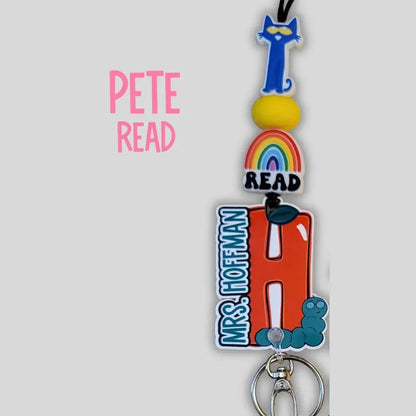 Mommie Peas Creations personalized lanyard with Pete the Cat, rainbow, apple charm, and caterpillar. Features "READ" and "MRS. HOFFMAN".