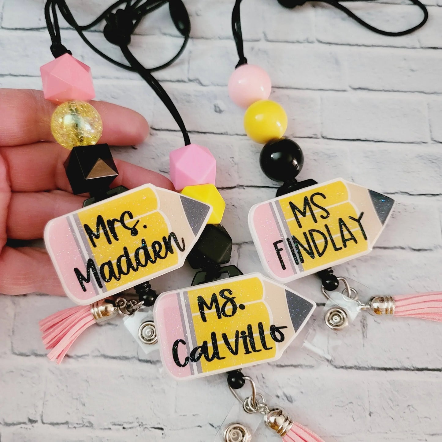 Mommie Peas Creations personalized teacher lanyard with glitter acrylic pencil charm, pink, yellow, and black beads, and retractable badge reel.