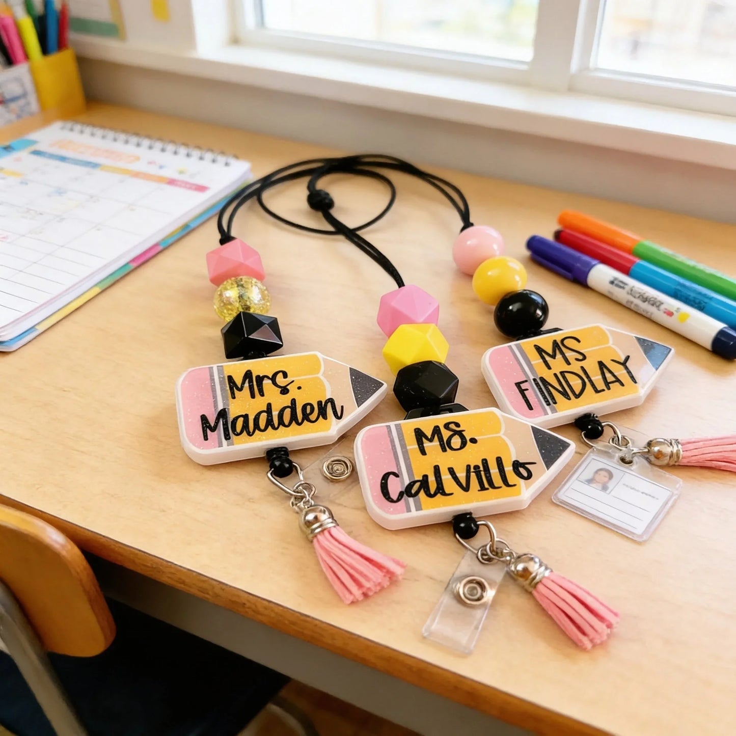 Mommie Peas Creations personalized teacher lanyard with glitter pencil charm, pink and yellow beads, and retractable badge reel.