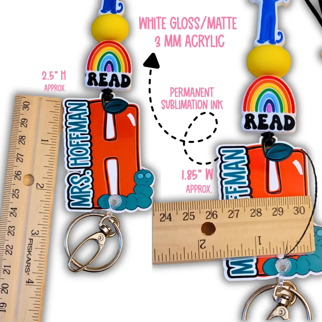 Colorful handmade teacher keychain with rainbow, yellow bead, orange letter, and ruler for size.