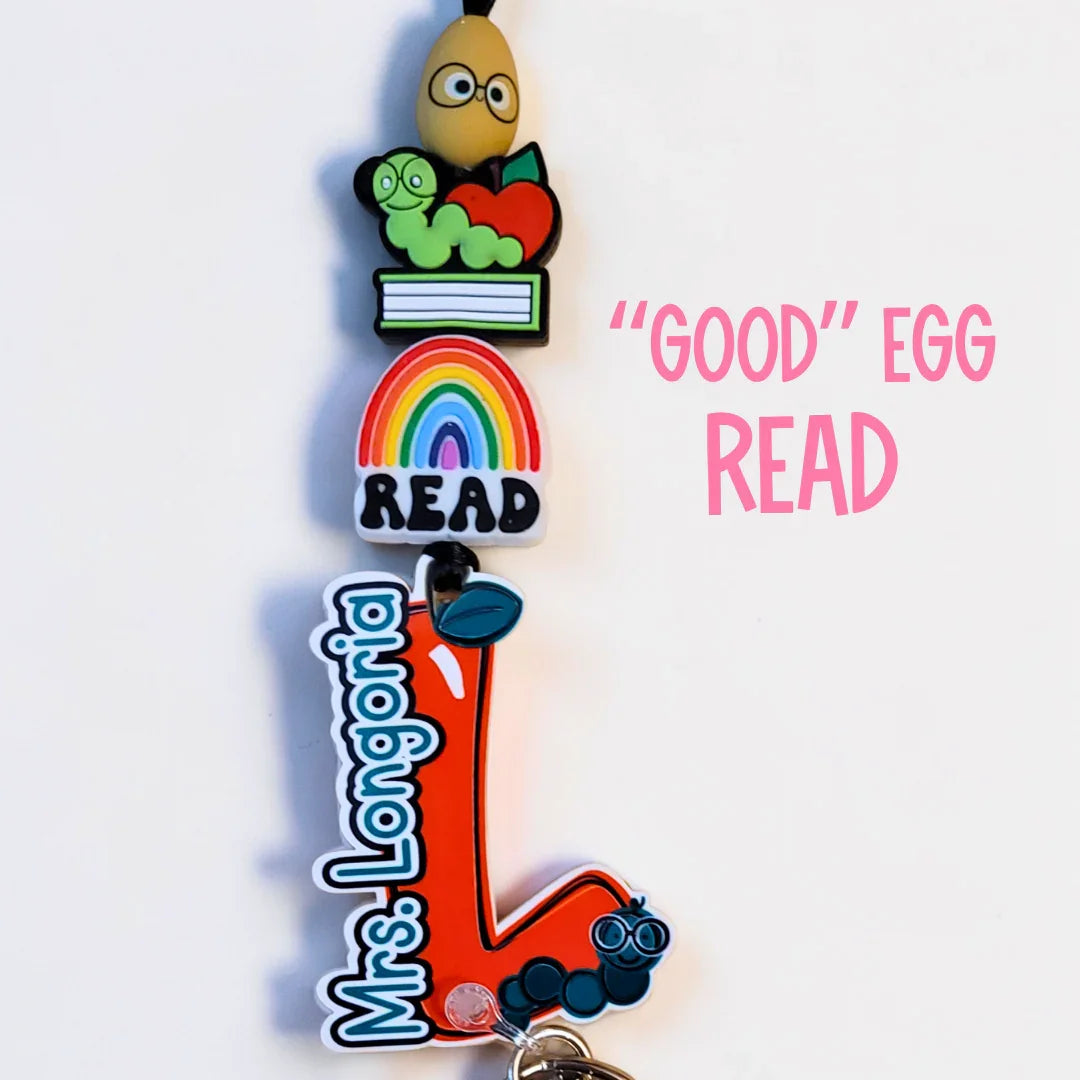 Handmade colorful teacher lanyard with egg, bookworm, apple, rainbow, and custom name charm.