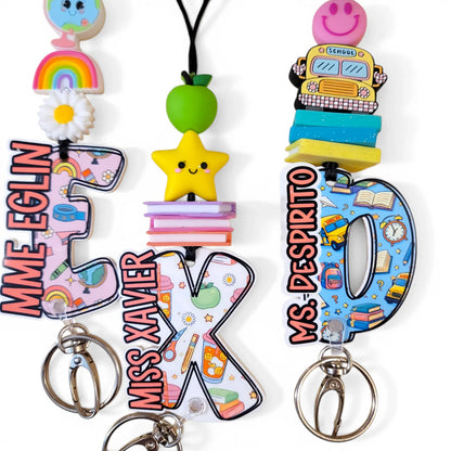 Colorful handmade teacher keychains with cute charms, rainbow, star, apple, and bus designs.