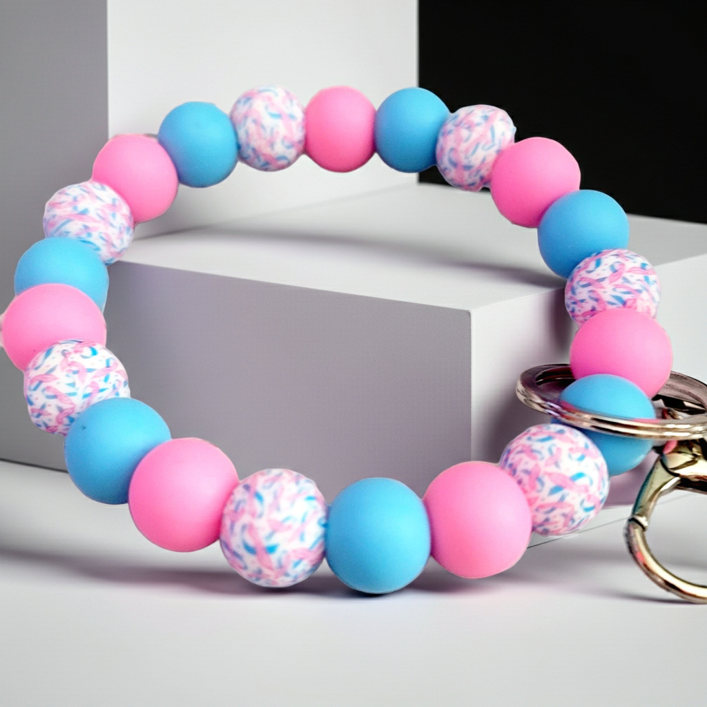 Colorful beaded bracelet keychain with pink, blue, and patterned round beads on white and black geometric background